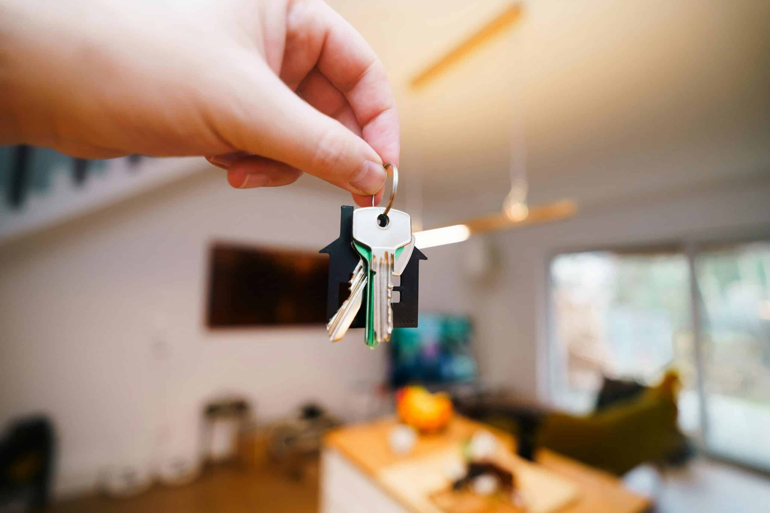 Hand holding out keys in a furnished room