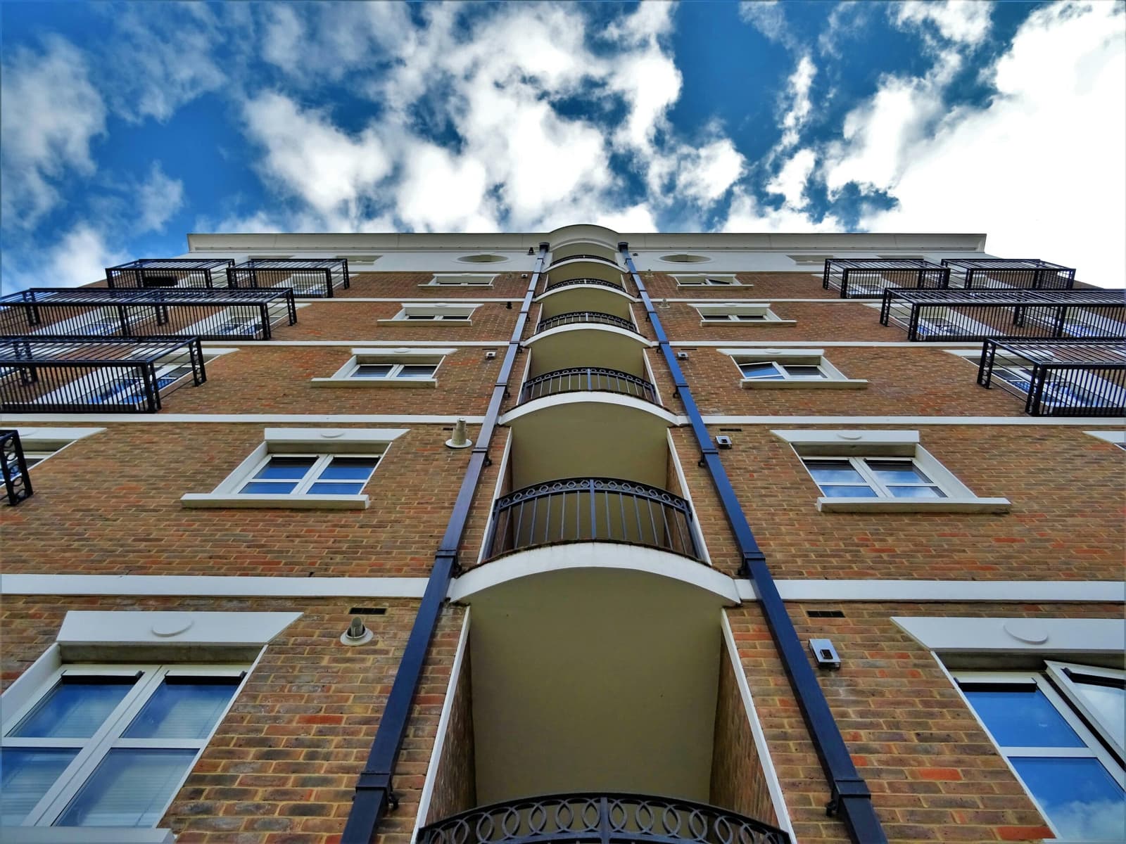 Looking up at the brick facade and balconies of an apartment block