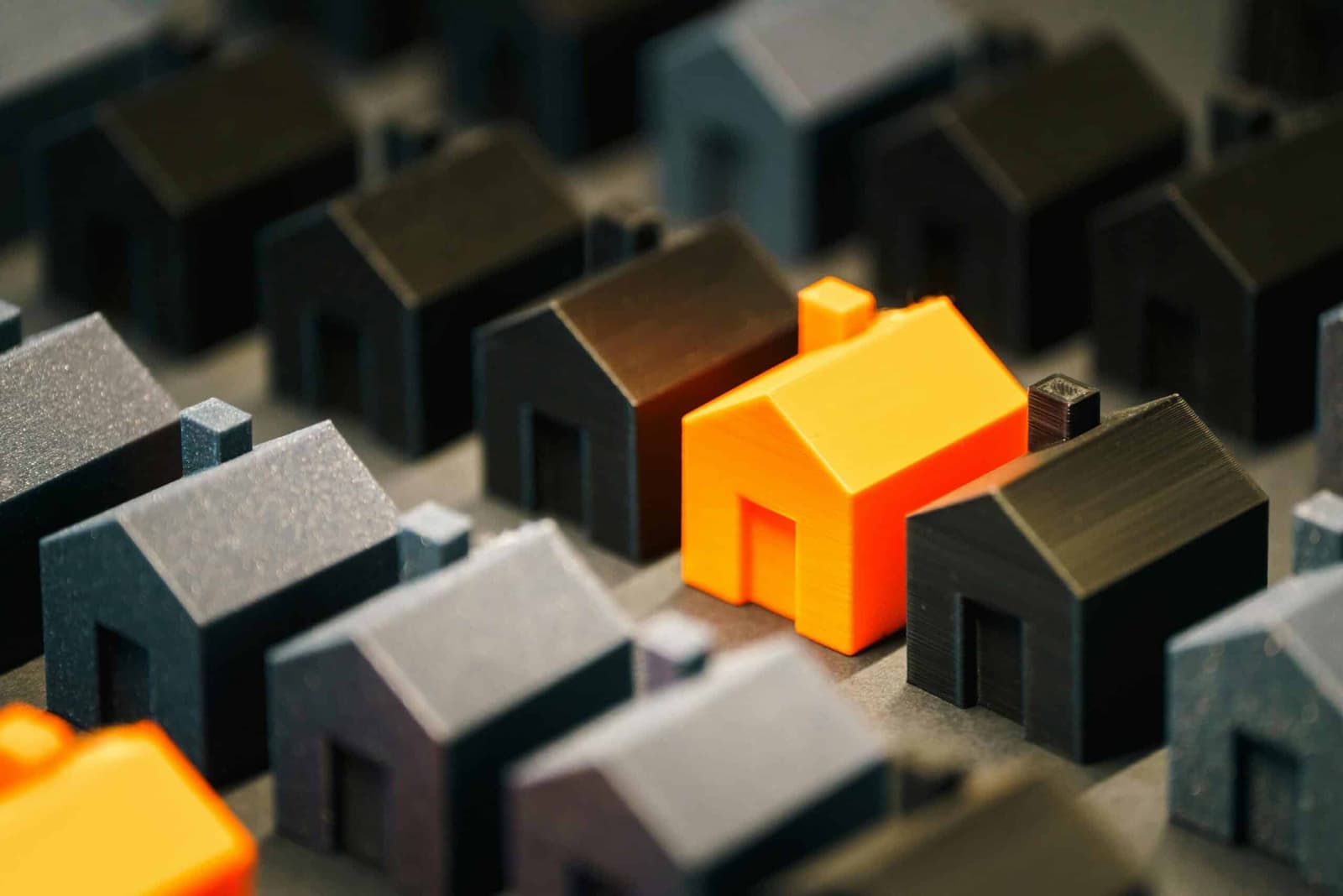Rows of grey model houses with two orange houses standing out