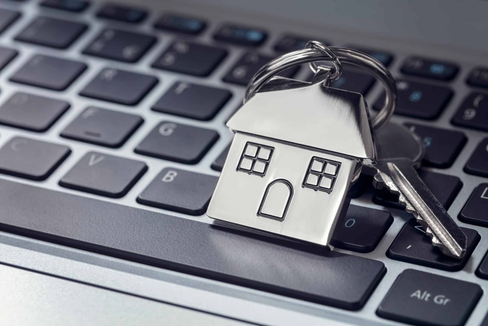 House shaped keyring and keys resting on a laptop keyboard