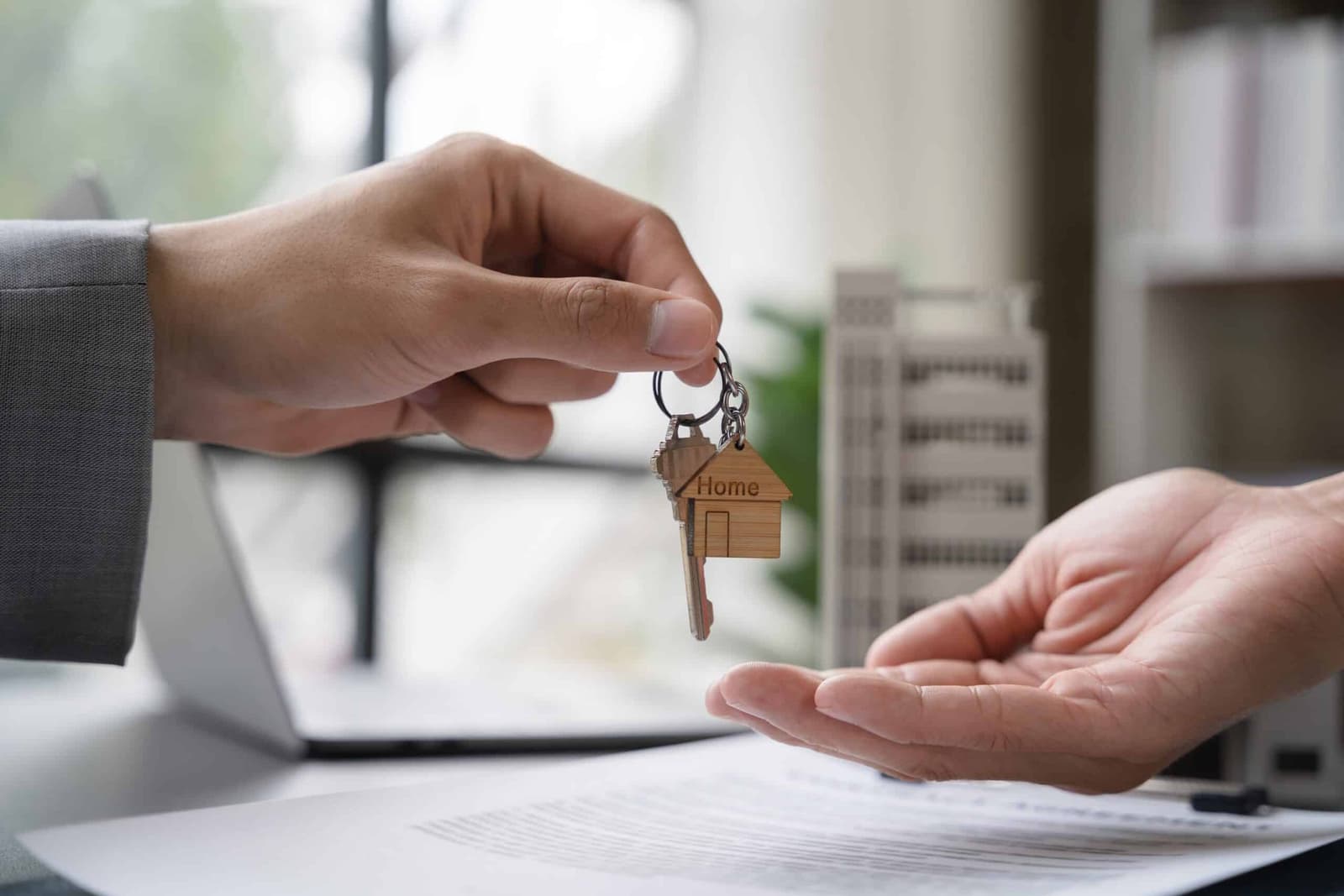 One person handing house keys to another over paperwork