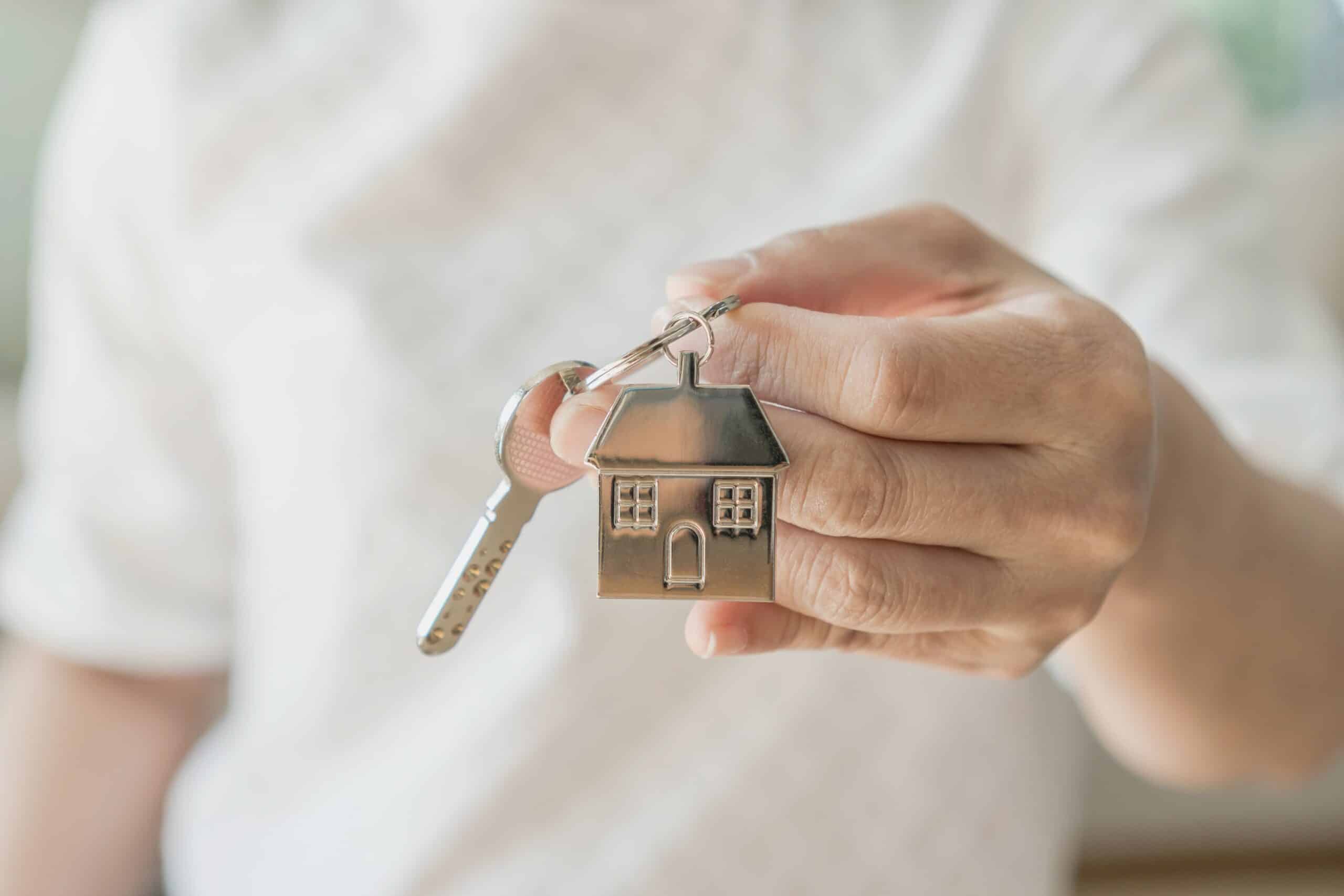 Hand holding a key with a house shaped keyring