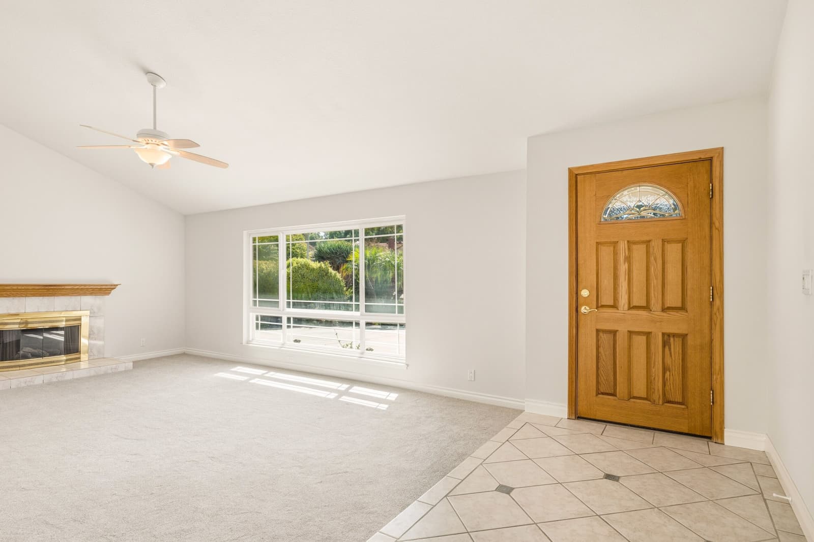 Empty unfurnished living room with bare carpet and a wooden front door